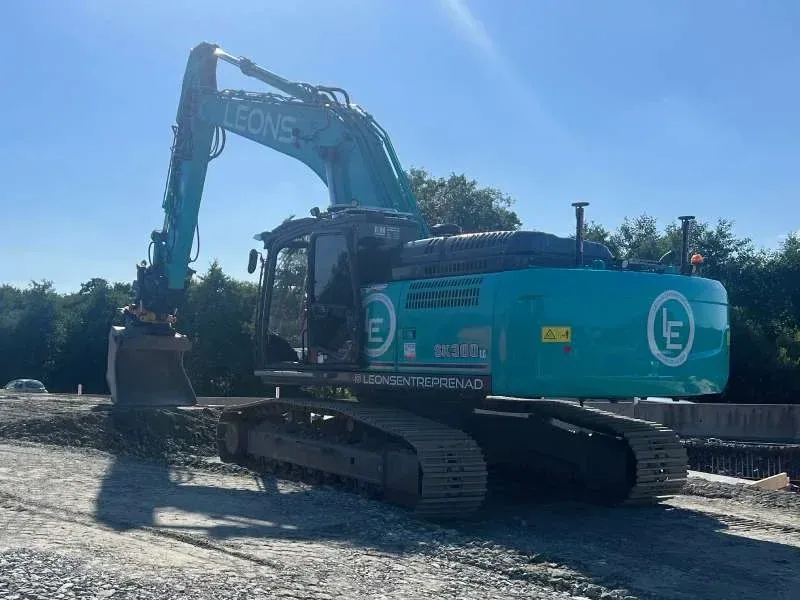 Turkos bandgrävare med Leons-logotyp på en grusbädd